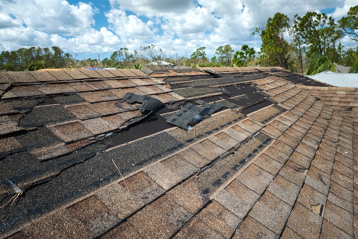 Damaged house roof with missing shingles after a storm