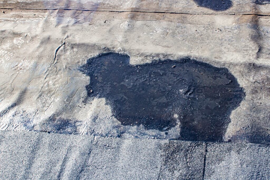 storm drain on a bitumen roof and rain puddles on an old unrepaired roof, the problem of leakage of old housing stock