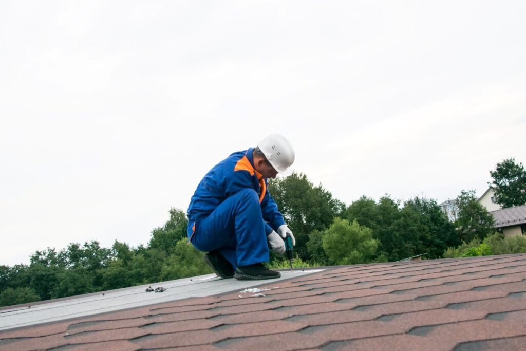 commercial roof leak detection worker installing shingles
