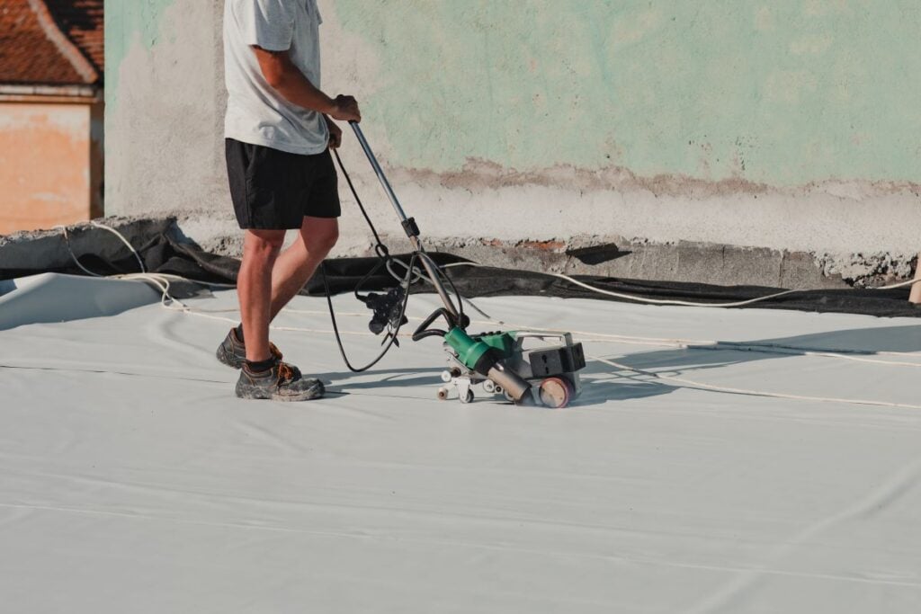 commercial roof maintenance tpo roofing installation technician sealing floor with heater machine on top of commercial building