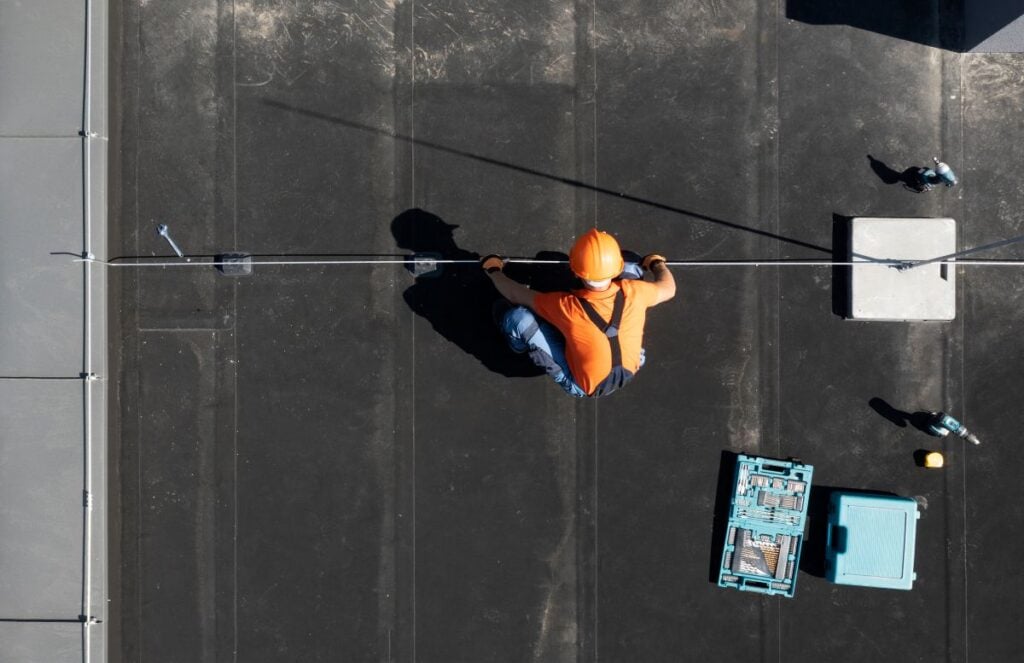 white glove experience worker using orange helmet inspecting commercial roof