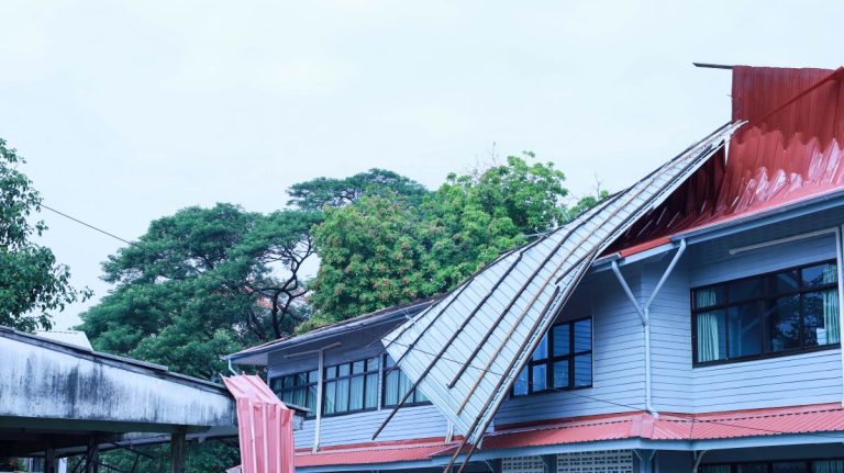 commercial roof storm damage metallic red roof building blue sliding