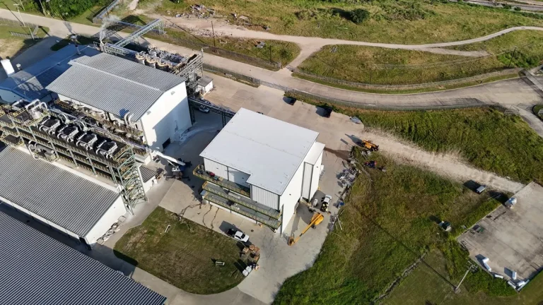 Aerial view of a white low-slope roof on an industrial building beside process equipment